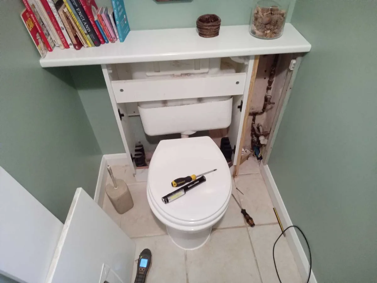 toilet with back panel removed exposing pipework during leak detection survey