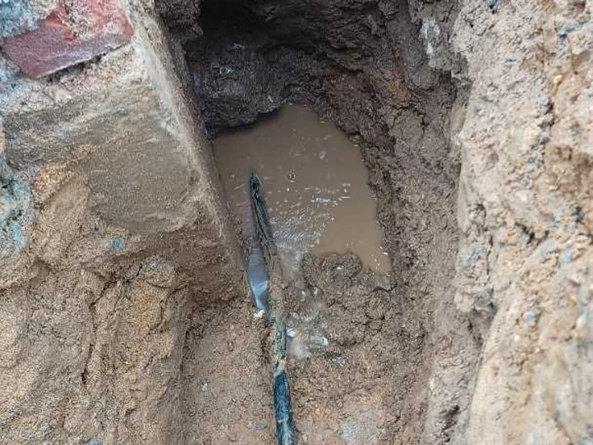 leak located at cracked 25mm black poly pipe with water pooling around manhole concrete wall
