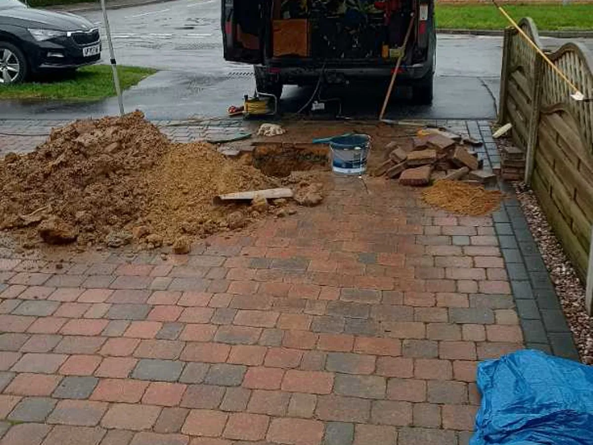 block paving driveway with excavated area backfilled and spoil beside van after works completed