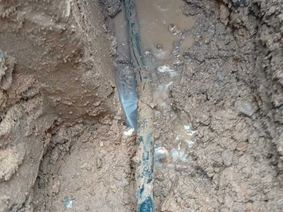 leak located at split 25mm black poly pipe close-up showing water escaping underground