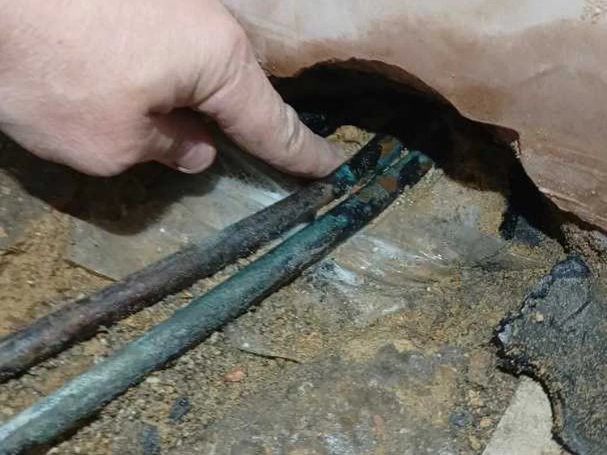 leak located at corroded 15mm copper pipework exposed beneath kitchen wall in concrete floor