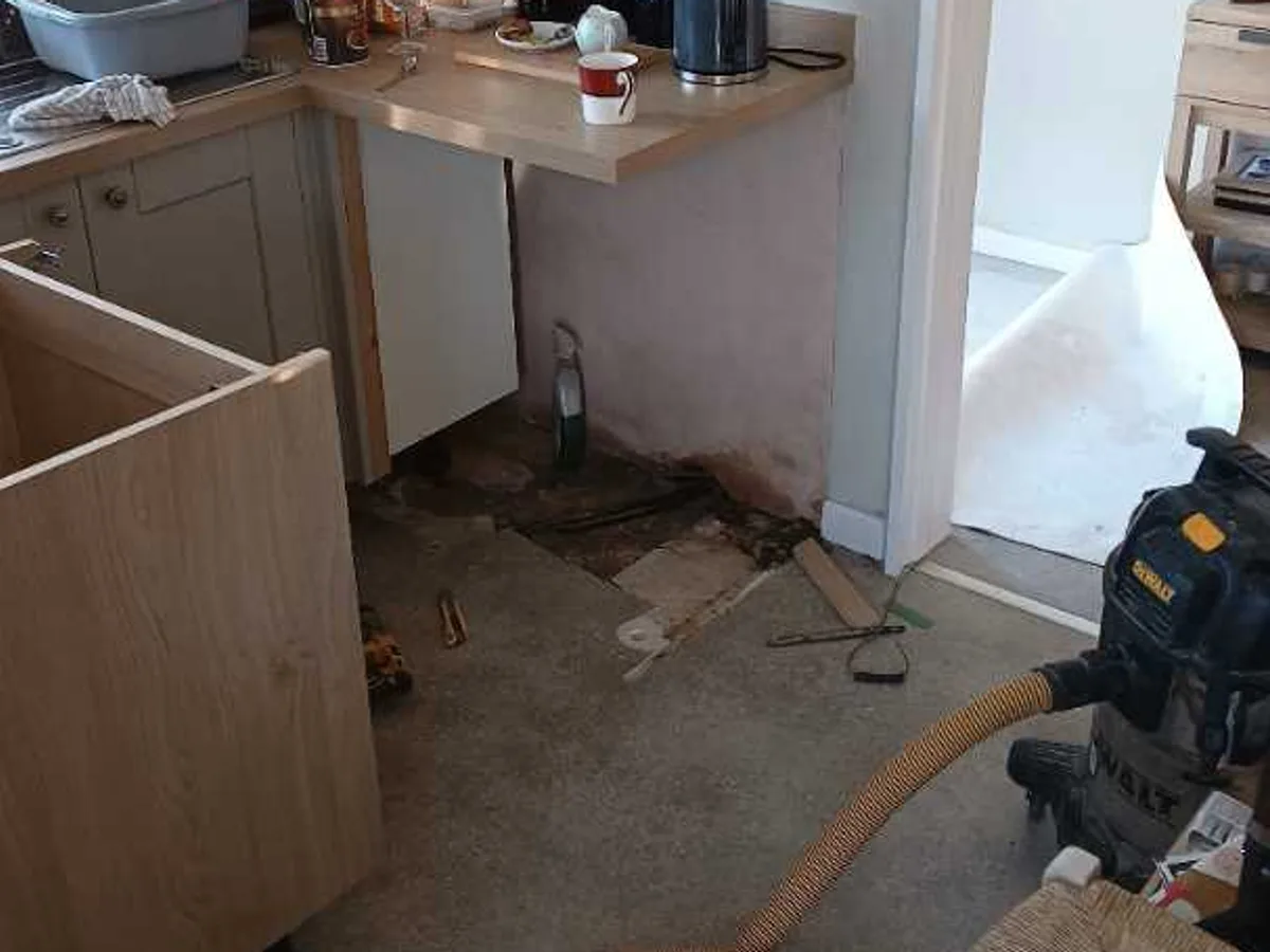leak found at exposed concrete floor beneath removed kitchen unit showing pipe access hole