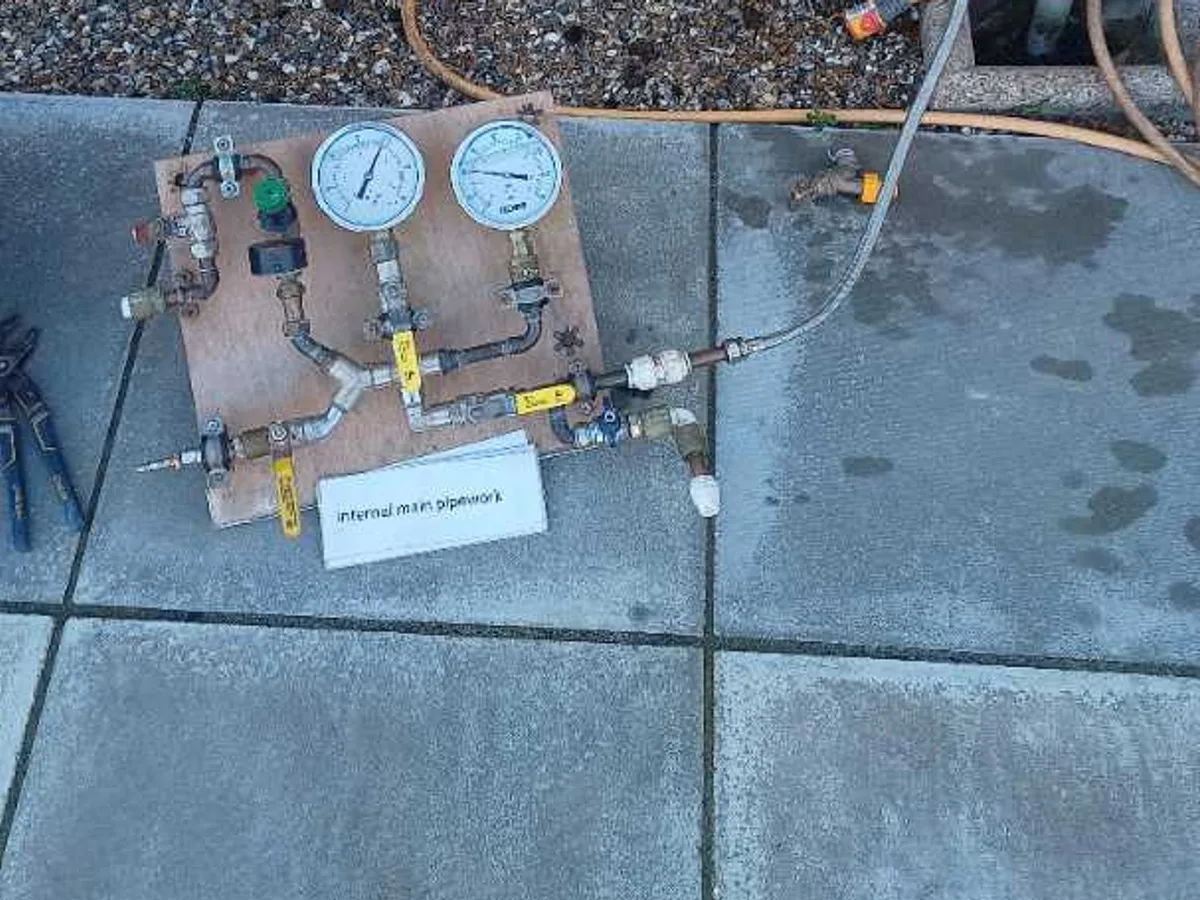 dual-gauge pressure test kit connected to outside tap wall plate during leak detection