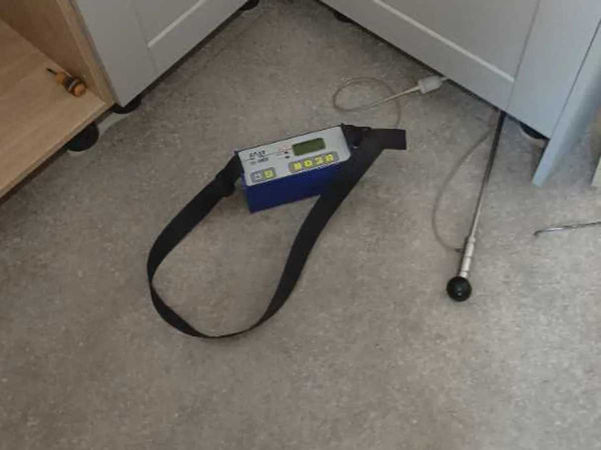 tracer gas detector on floor beside kitchen base units during leak detection survey