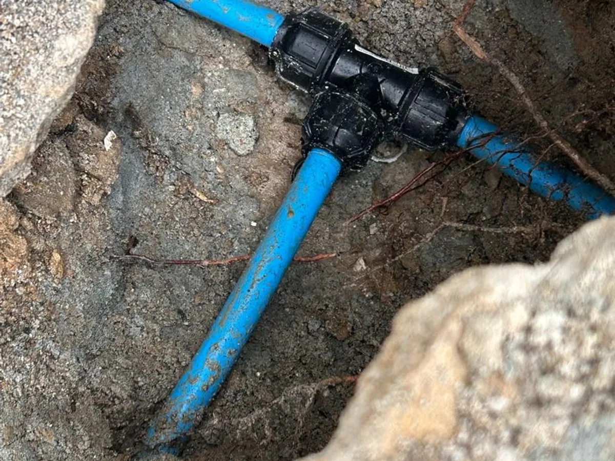 fault identified at excavated blue mains tee fitting beneath kitchen patio — leak located at