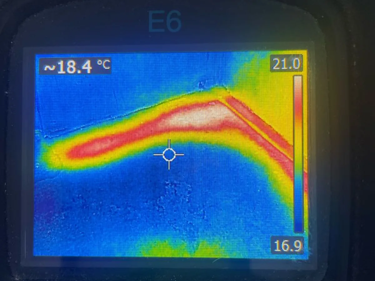 thermal imaging camera screen showing heat anomaly in utility room floor during leak detection