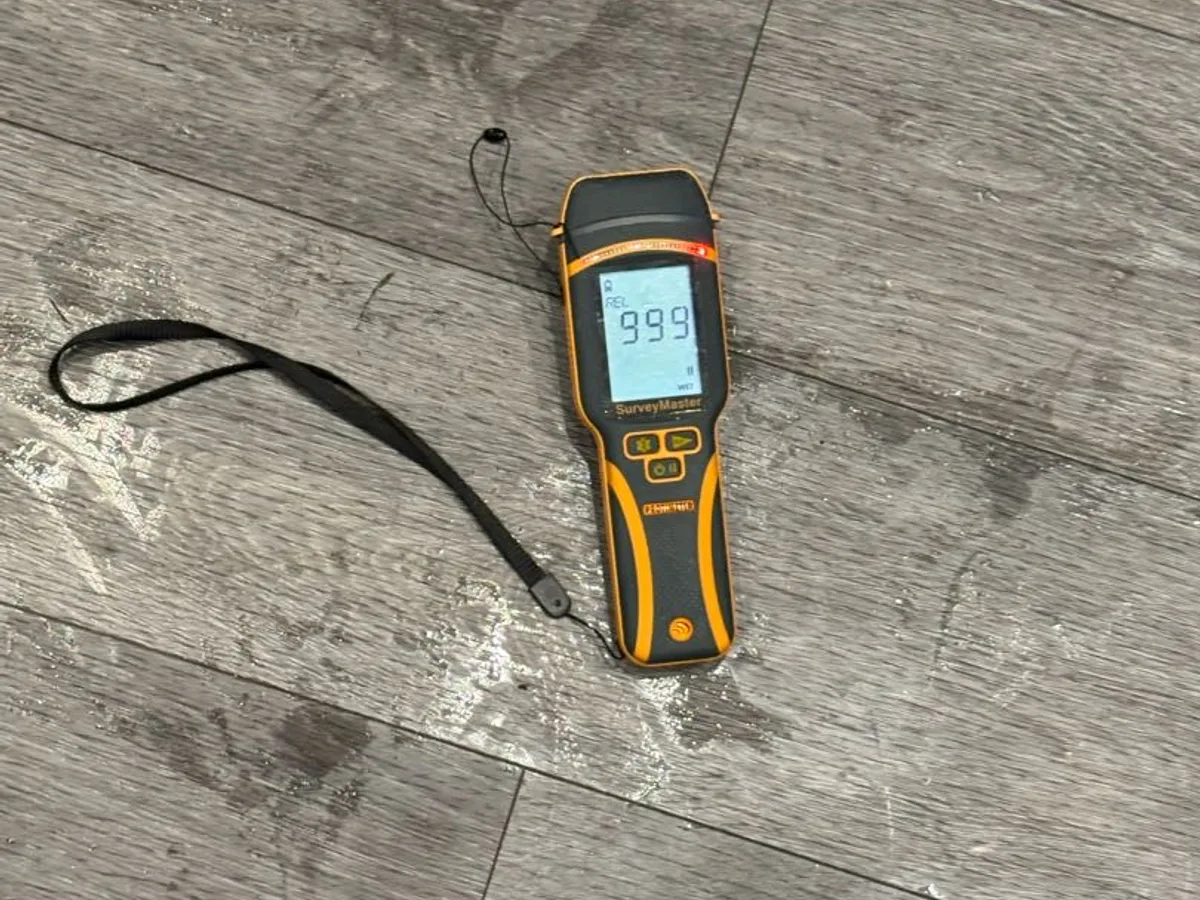 moisture meter reading 999 on saturated kitchen floor during leak detection