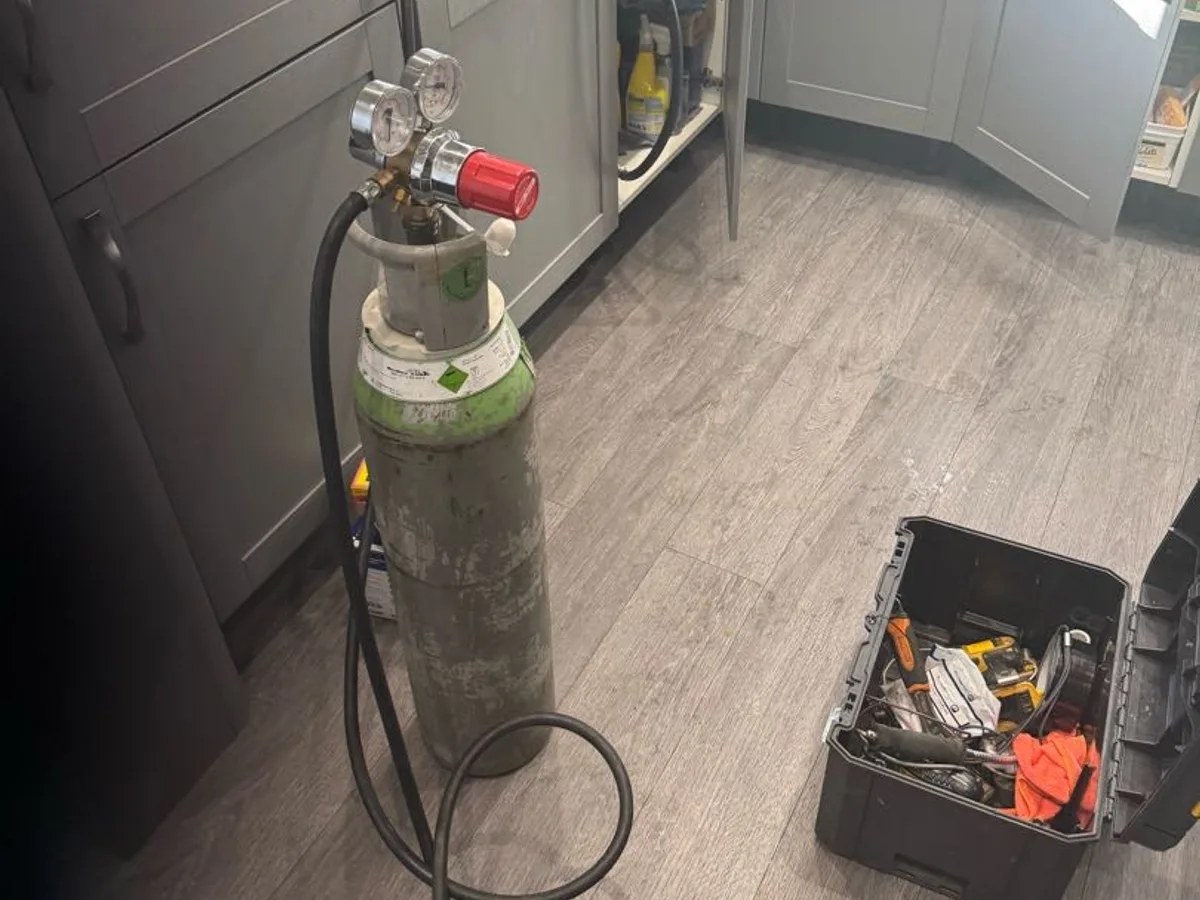 tracer gas cylinder connected to pipework in kitchen during leak detection