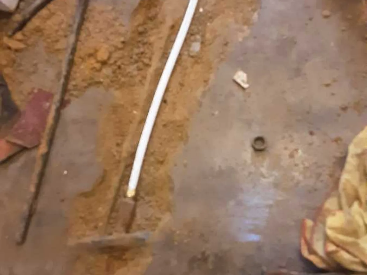 new section of 15mm white plastic pipe laid in concrete trench as repair in progress