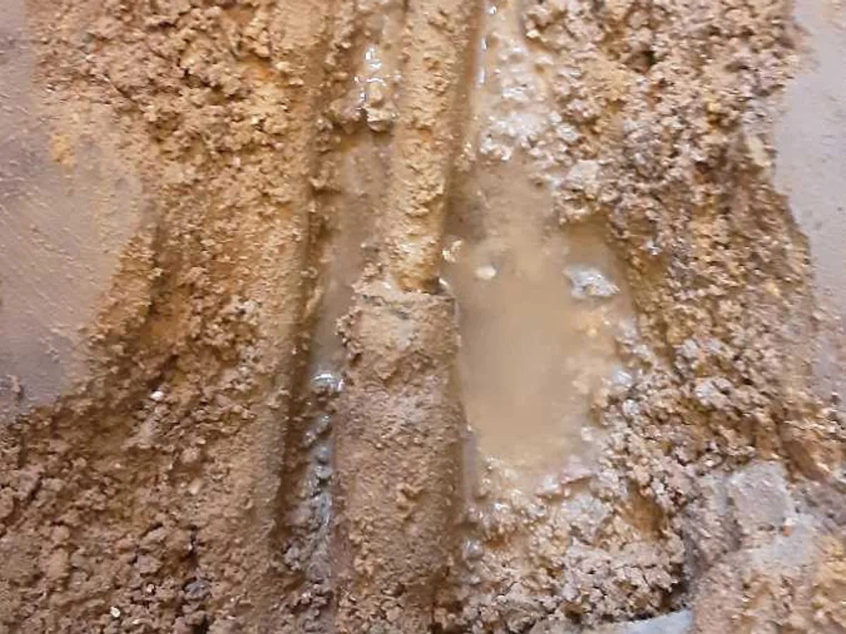 leak located at saturated concrete subfloor with water pooling around exposed copper pipework
