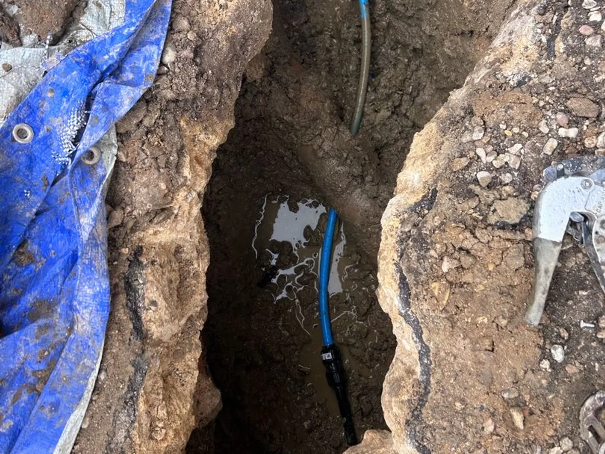 new blue mains water pipe section installed in excavated trench as repair completed