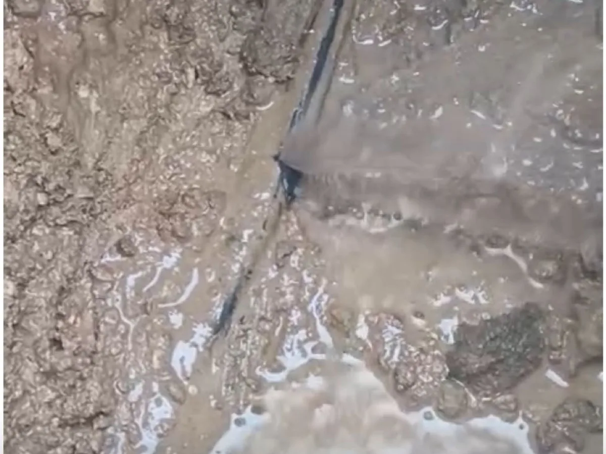 leak located at exposed underground mains pipe in waterlogged excavation trench