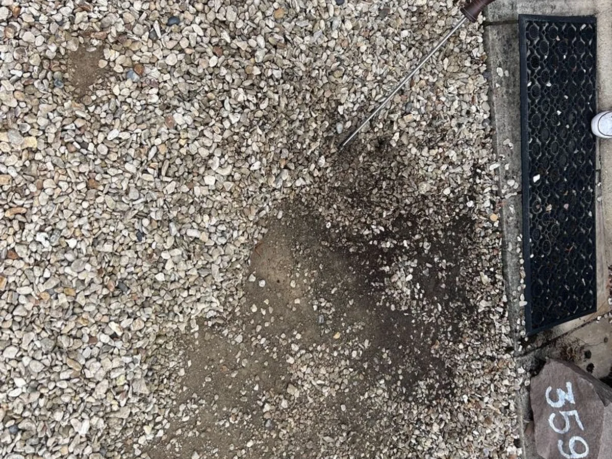 saturated gravel driveway with dark wet patch before leak detection works