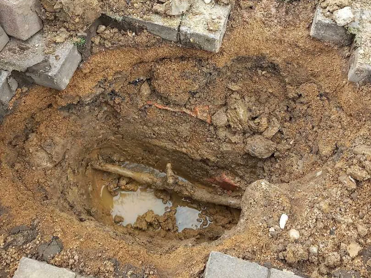 leak located at excavated driveway revealing waterlogged soil around buried lead supply pipe