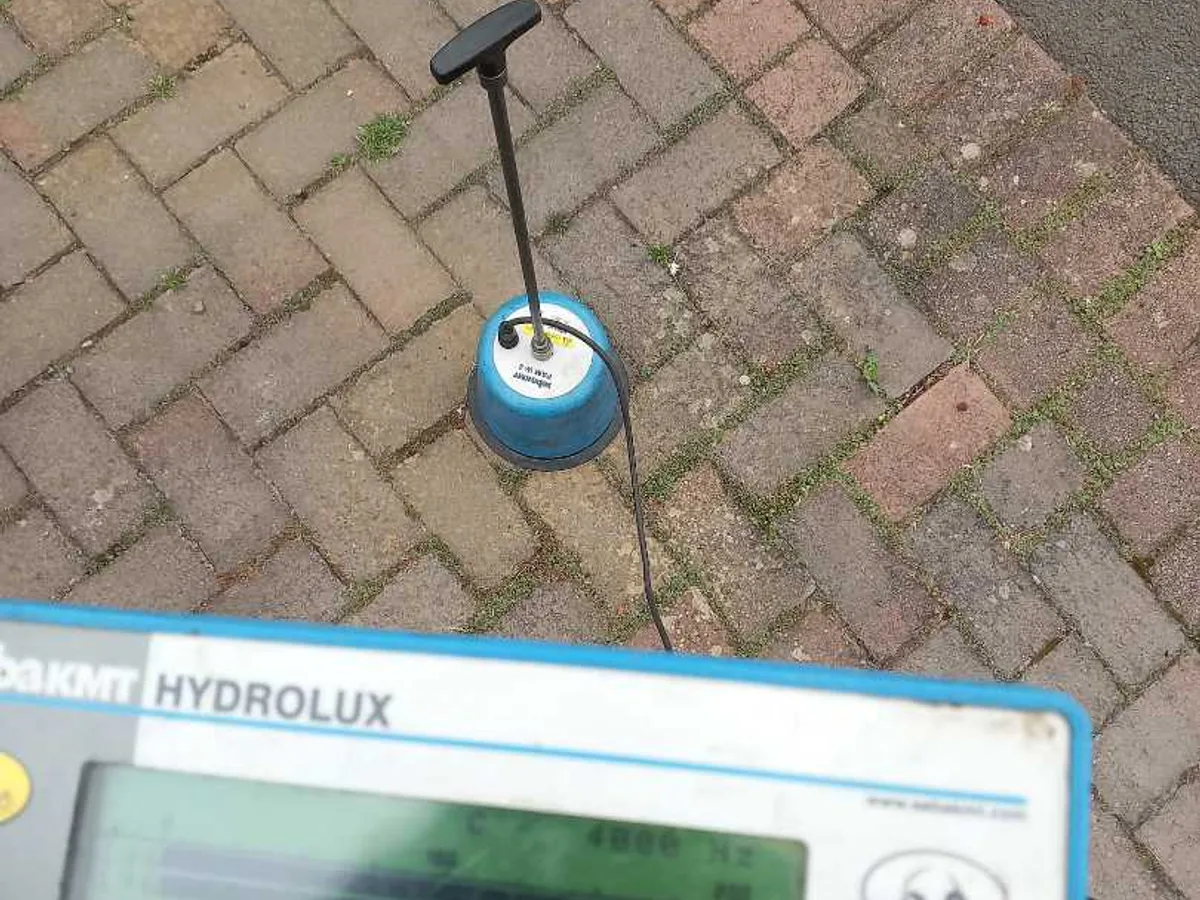 tracer gas detector probe on brick paving driveway during leak detection investigation