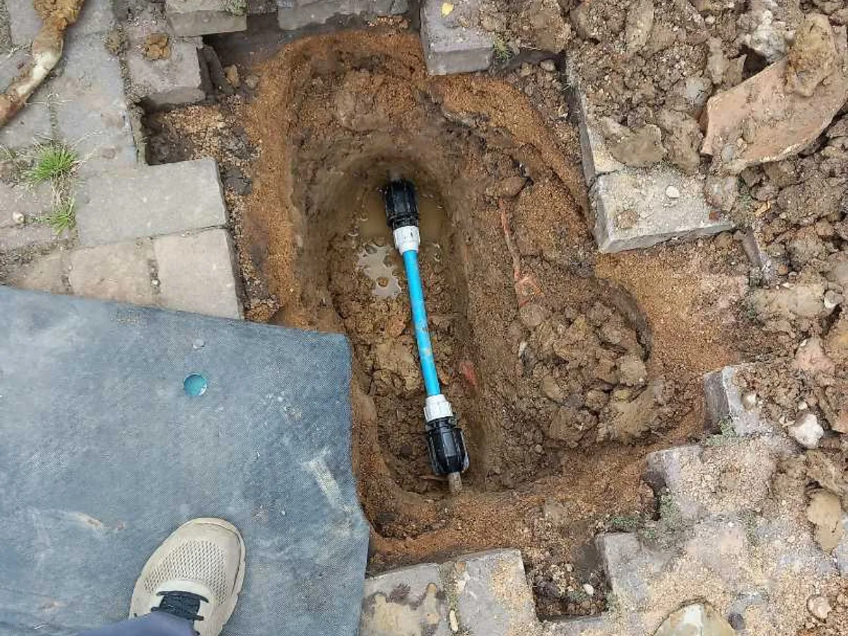 universal transit coupling fitted to lead mains pipe in excavated driveway as repair completed
