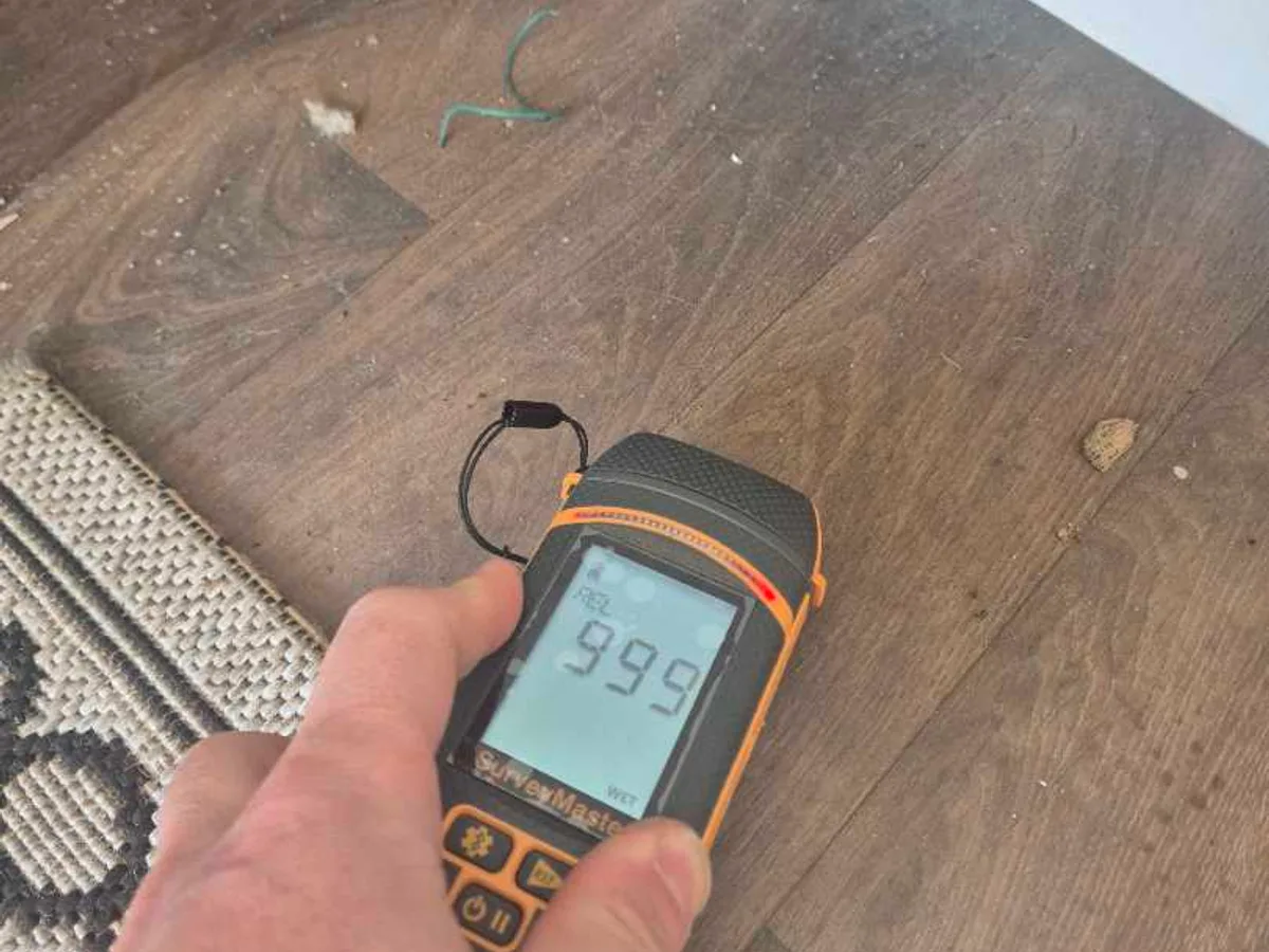 damp meter showing reading of 99.9 on converted garage floor during leak detection