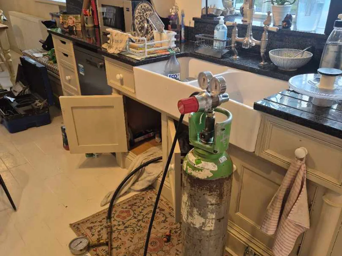 tracer gas cylinder connected to water mains supply under kitchen sink during leak detection