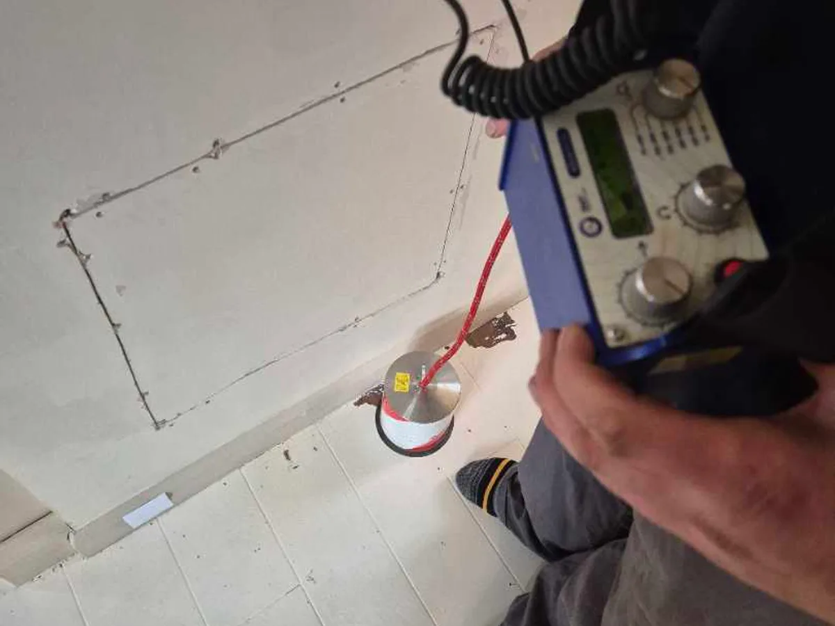 tracer gas detector used on lounge floor with marked excavation outline during leak detection