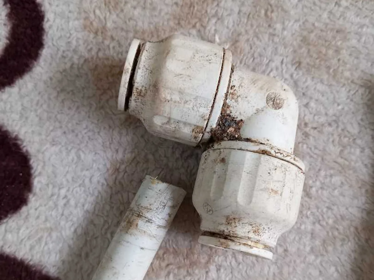 fault identified at corroded plastic push-fit elbow fitting removed from below concrete floor — leak located at