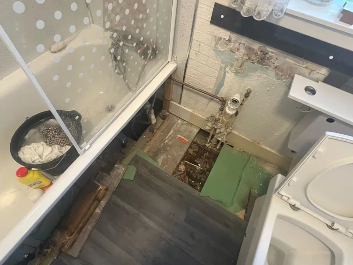bathroom with floorboard removed and exposed pipework before leak detection works