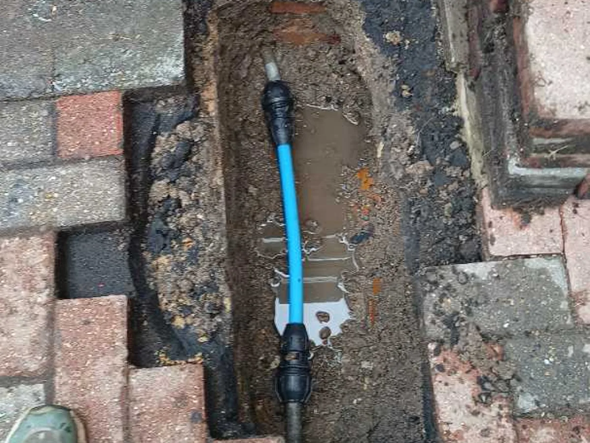 new blue MDPE pipe with compression couplings repair completed in garden trench