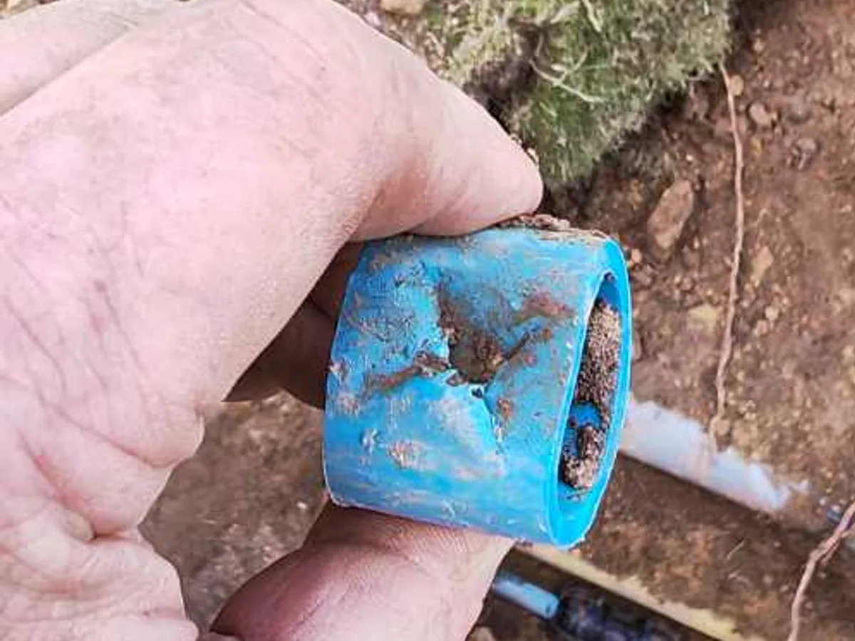leak identified at removed section of blue mains pipe showing puncture hole