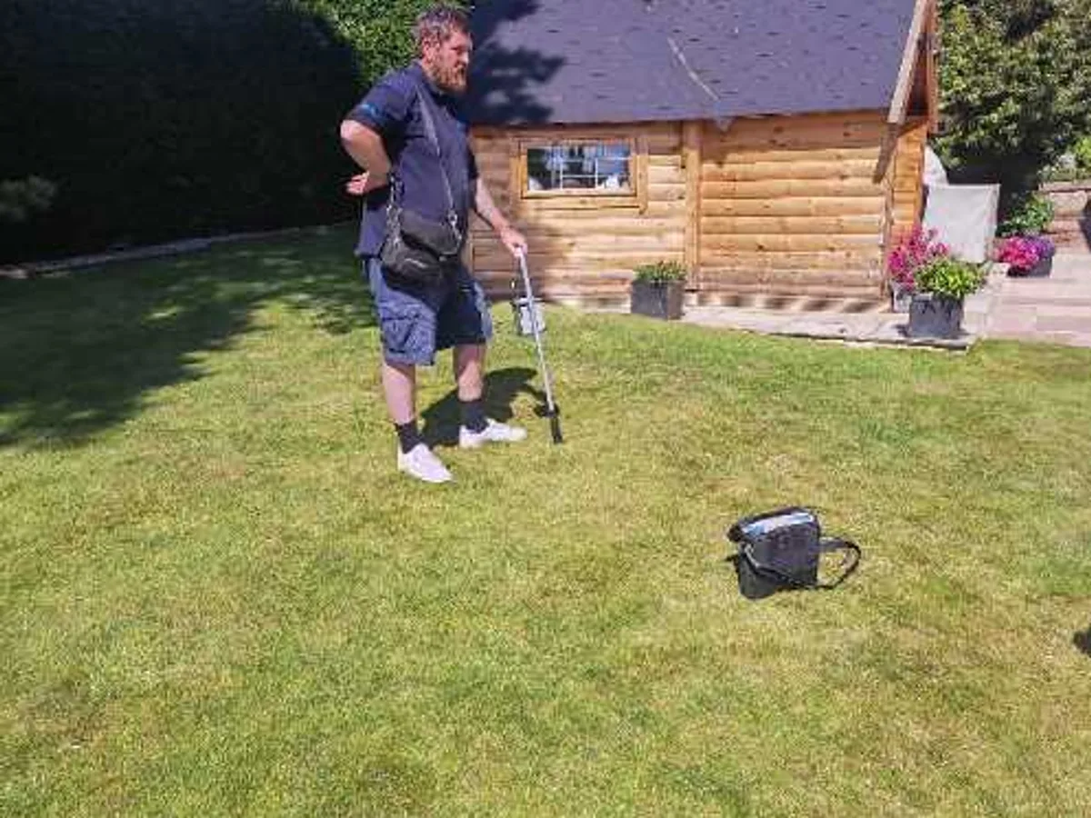 engineer sweeping lawn with tracer gas detection probe during leak detection survey