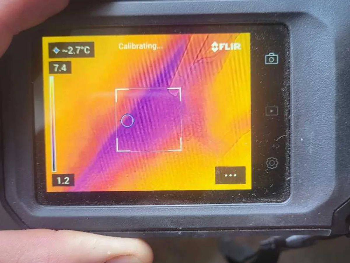 thermal imaging camera screen showing cold anomaly on floor during leak detection survey