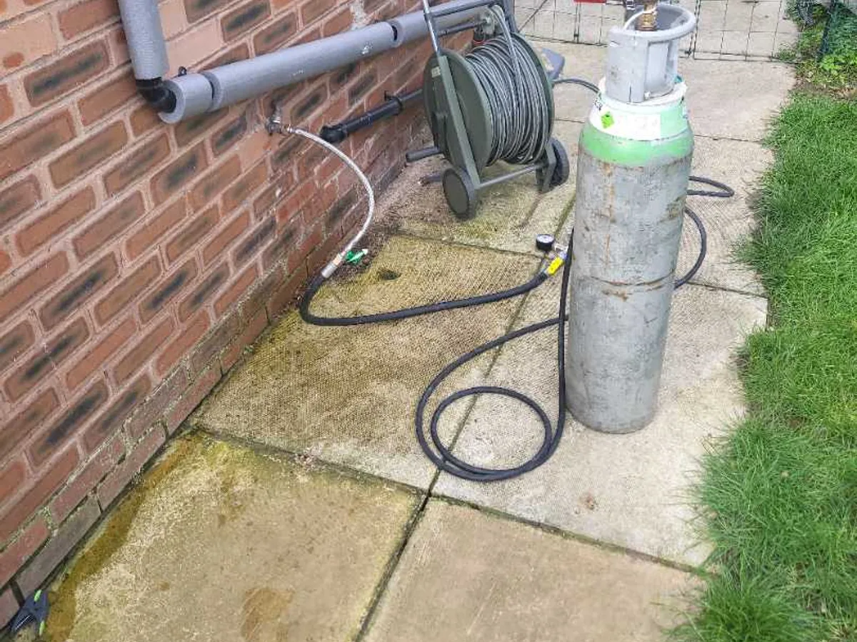 tracer gas cylinder and hose reel connected to external pipework during leak detection