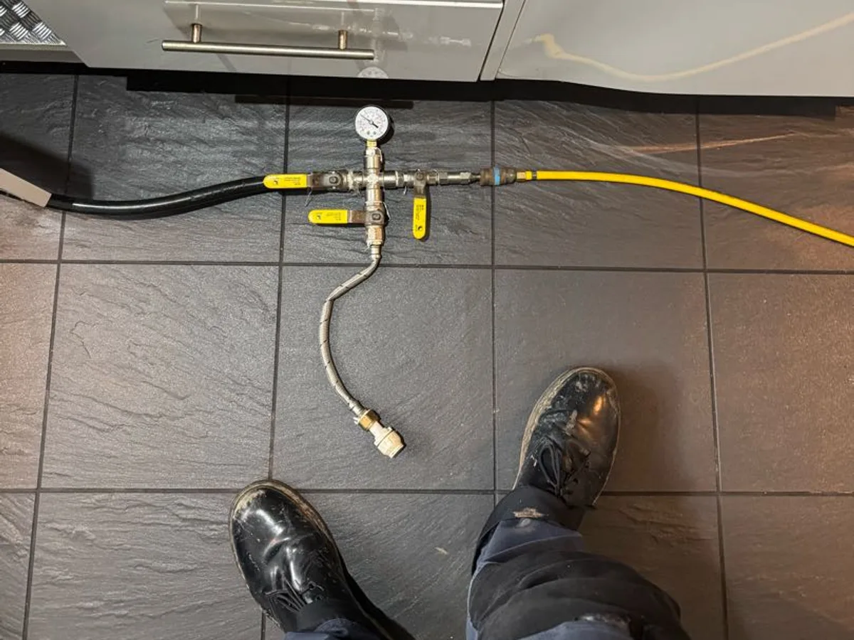 tracer gas injection rig with pressure gauge connected to kitchen pipework during leak detection