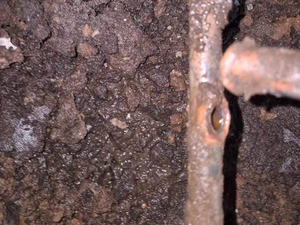 fault identified at corroded copper pipe with snapped branch below garage floor level — leak located at