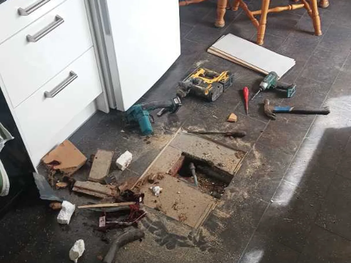 leak exposed at access opening cut through kitchen laminate and chipboard floor — leak located at