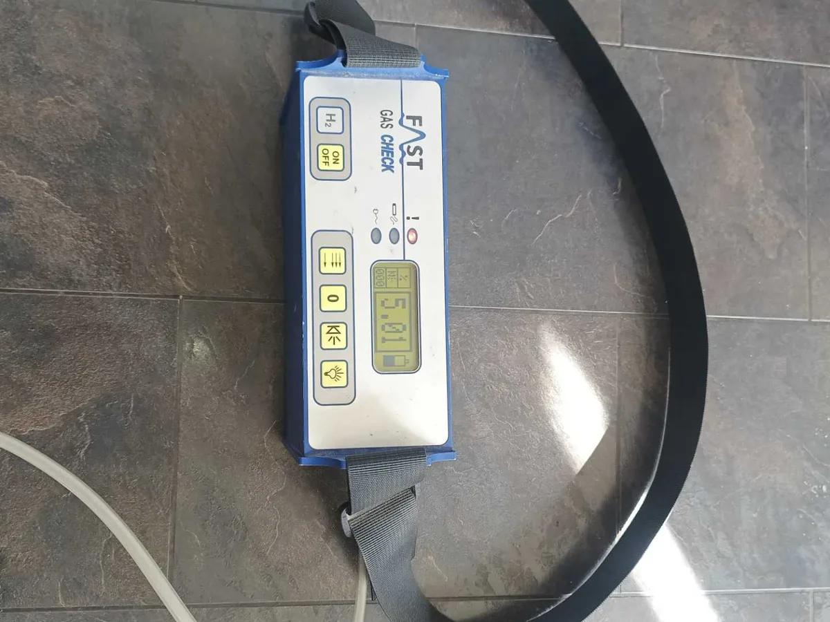 tracer gas detector unit displaying reading on kitchen floor during leak detection