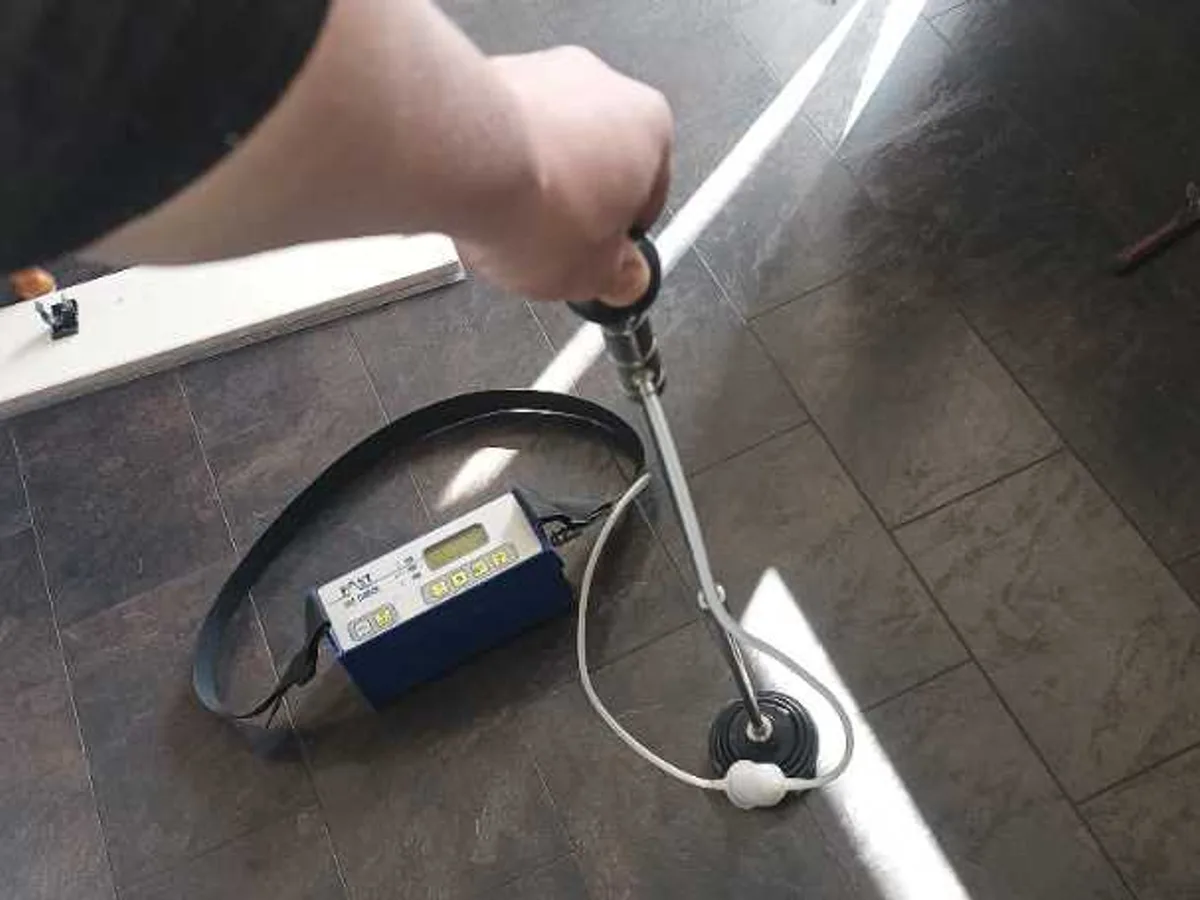 tracer gas detector probe being swept across kitchen floor during leak detection