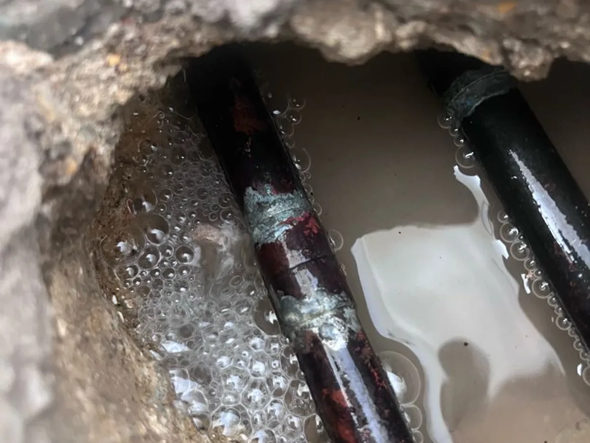 leak located at corroded 15mm hot pipe exposed beneath concrete floor in hallway