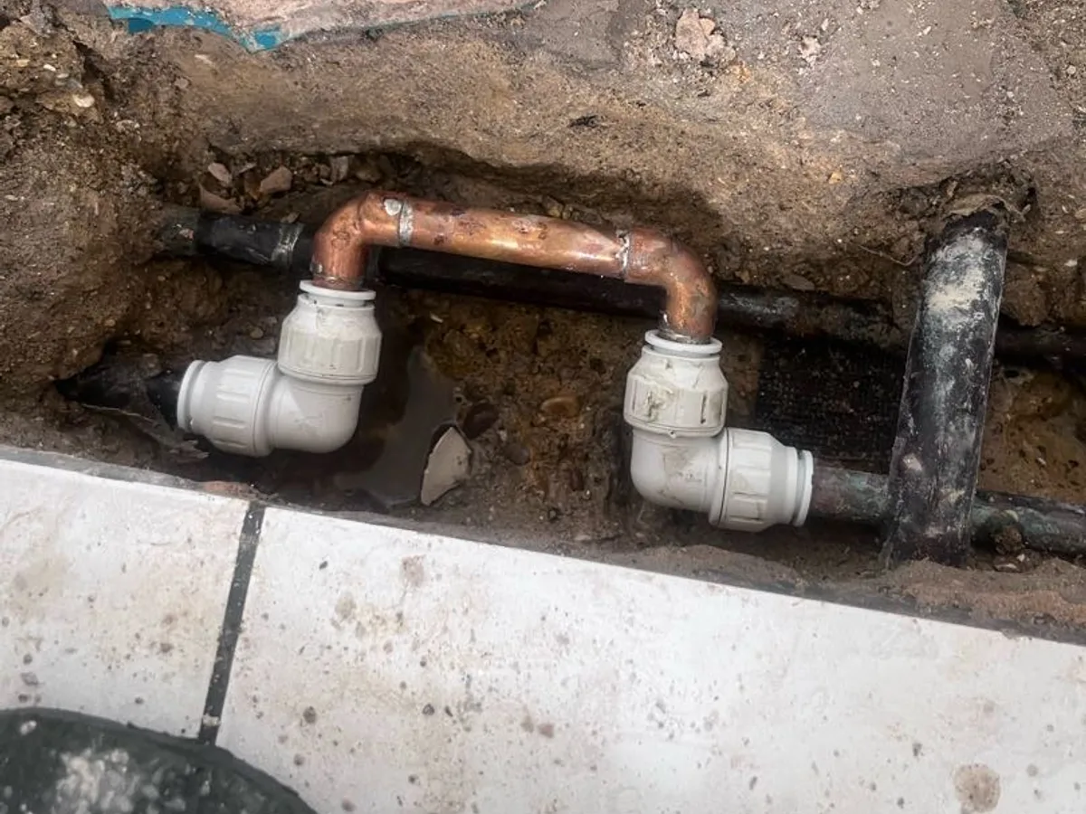 new copper pipe section with push-fit fittings installed as repair completed beneath hallway floor