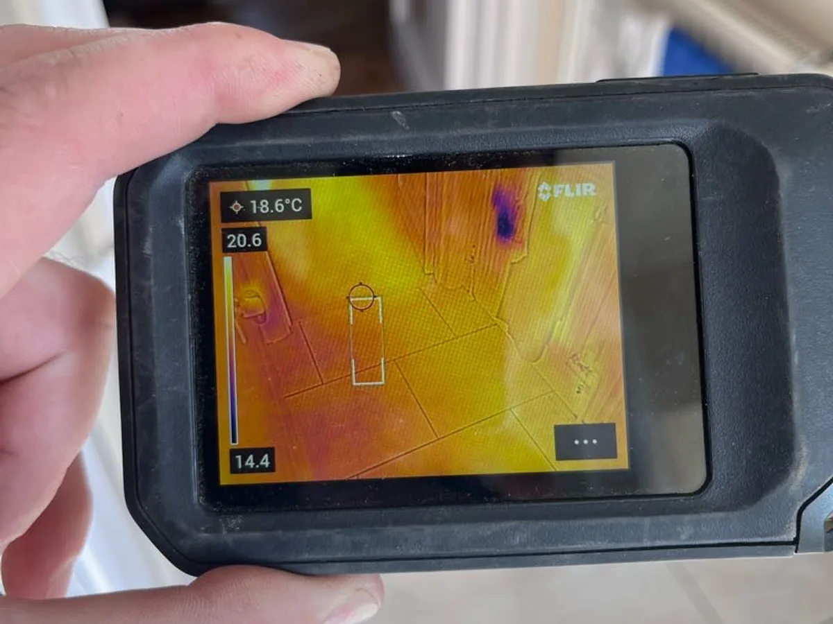 thermal imaging camera screen showing heat anomaly in floor during leak detection survey