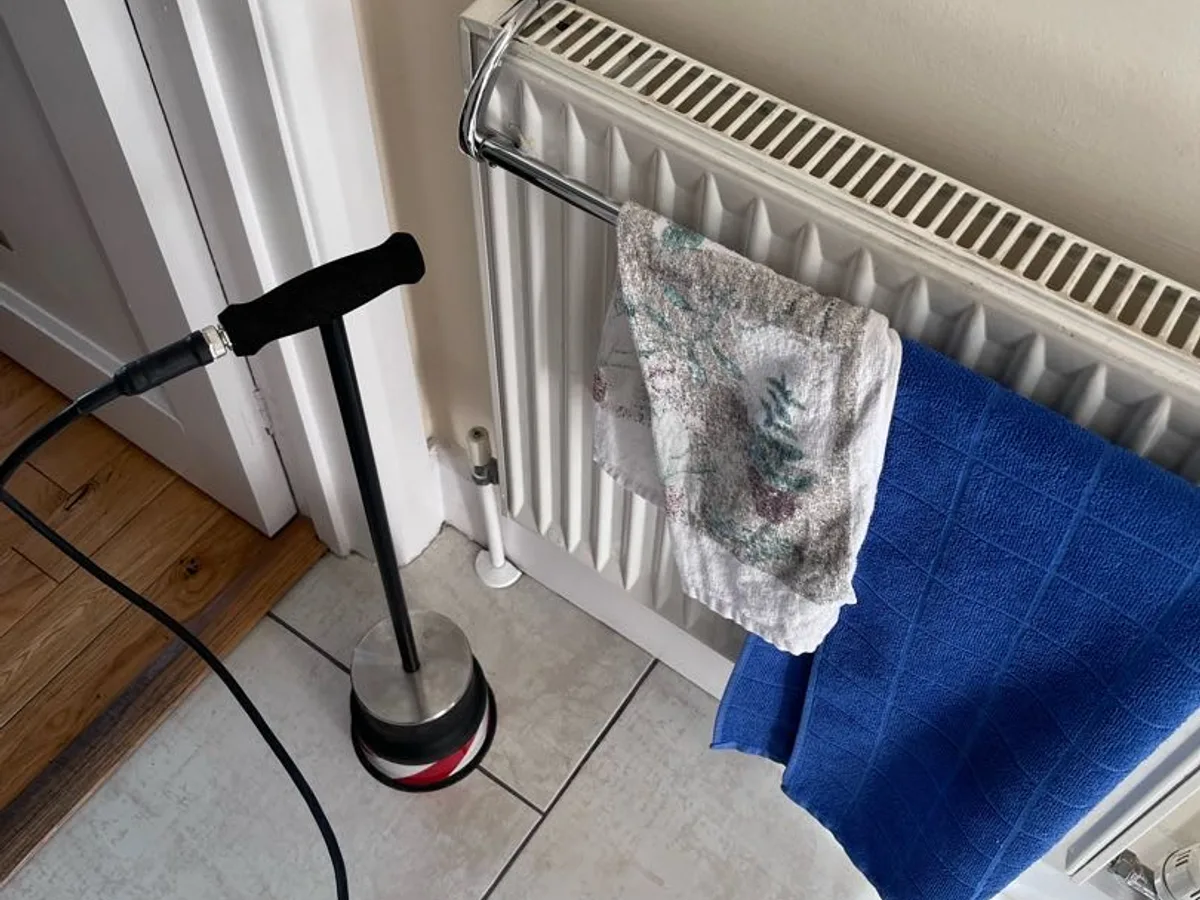 tracer gas detection probe on tiled floor beside radiator during leak detection