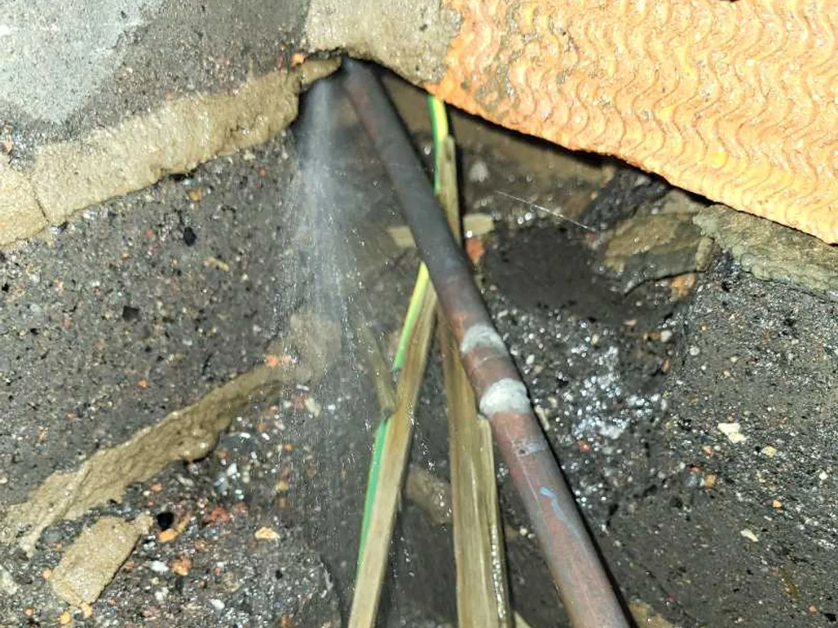 leak located at copper mains pipe with water spraying from pinhole beneath lounge floor