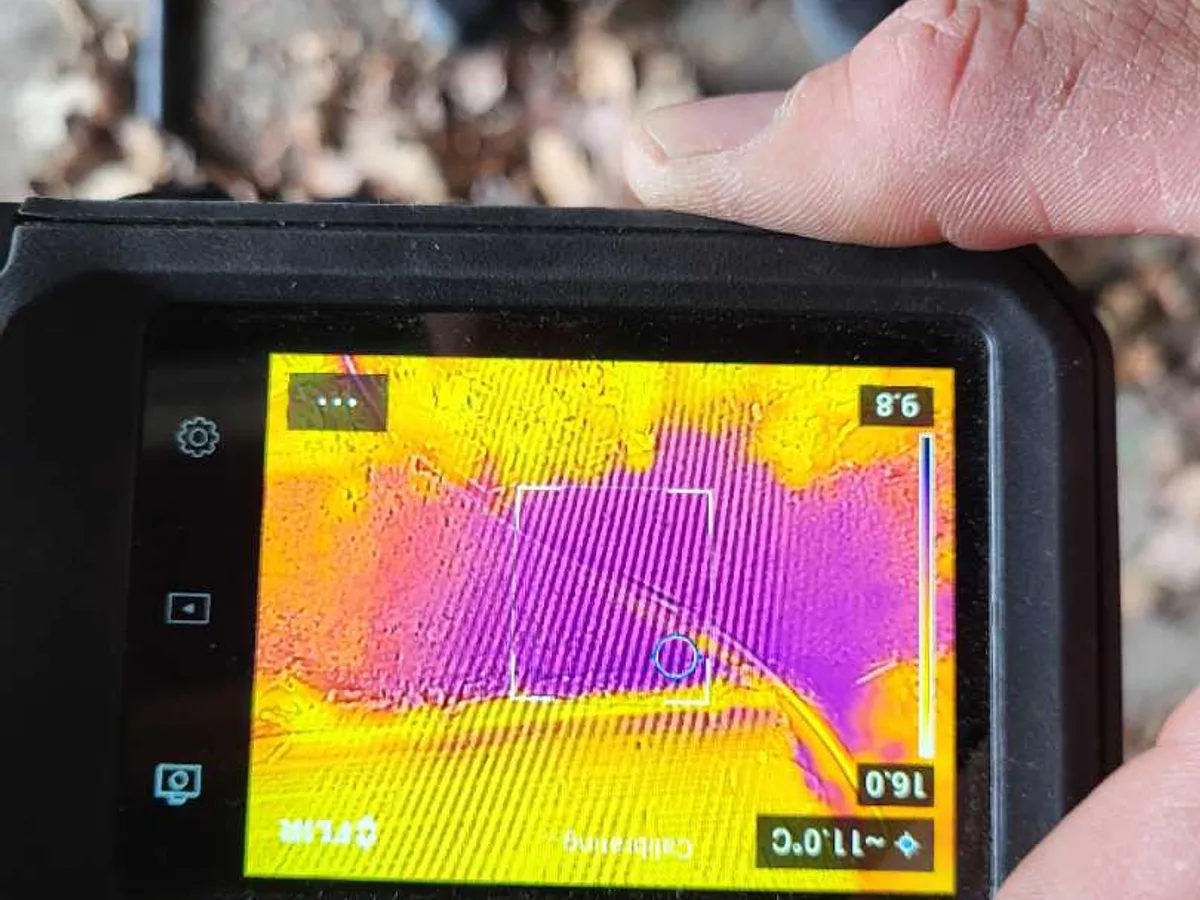 thermal imaging camera screen showing cold anomaly beneath garage floor during leak detection