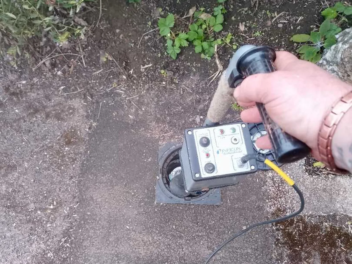 tracer gas detector held over external water meter during leak detection