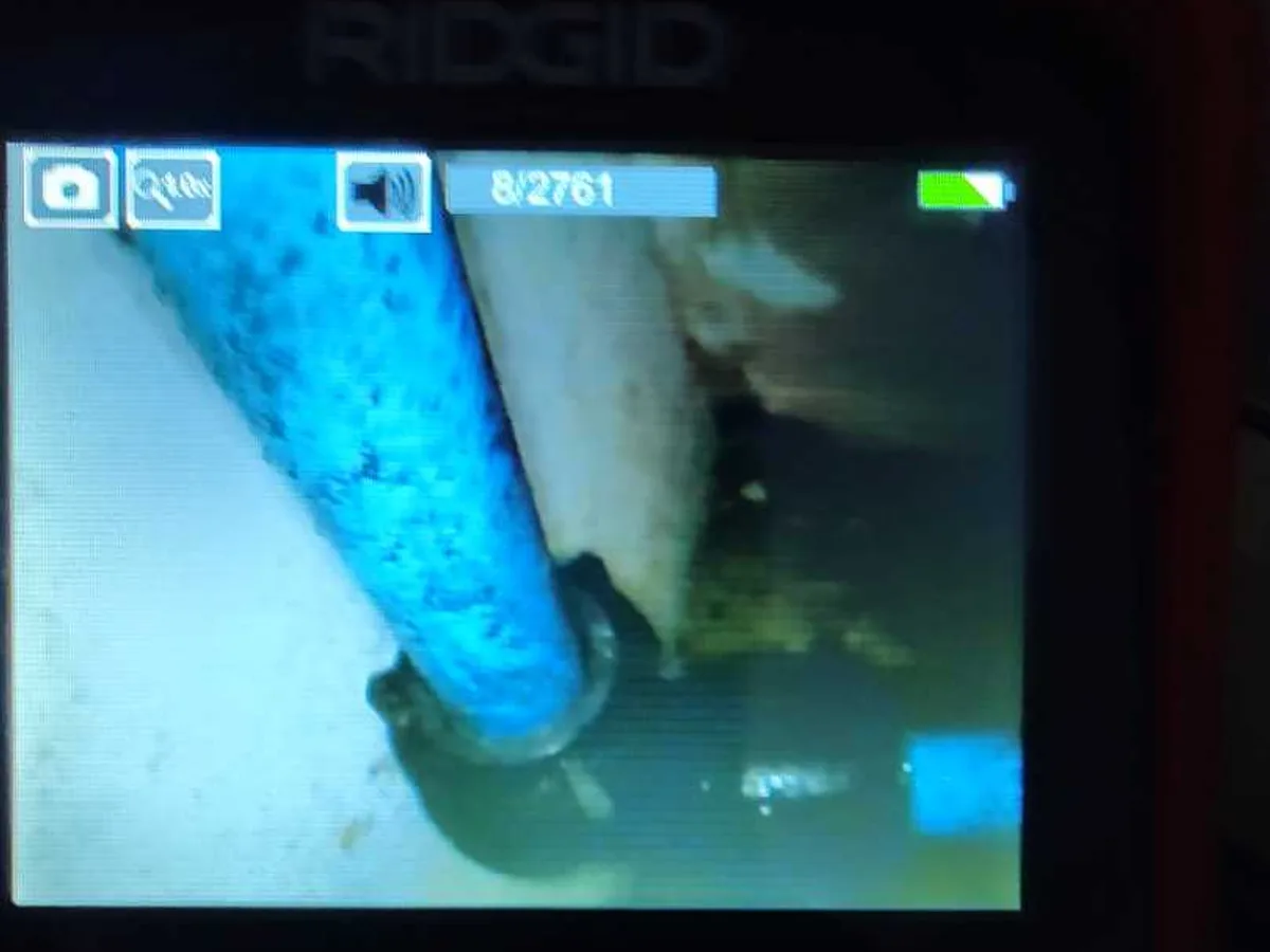 borescope camera screen showing blue poly pipe behind bathroom tiles during leak detection