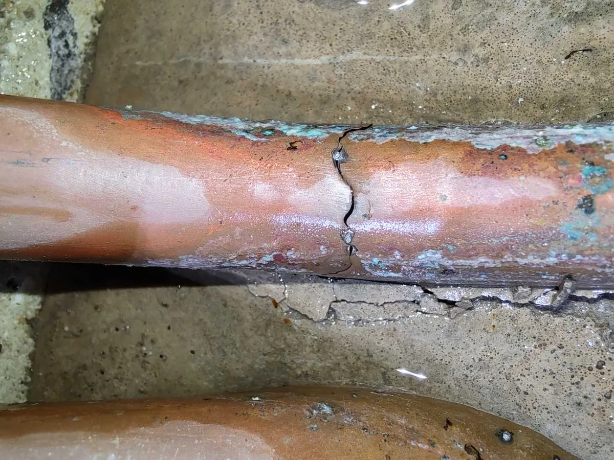 leak located at cracked solder joint on 15mm copper pipe beneath corridor floor tiles
