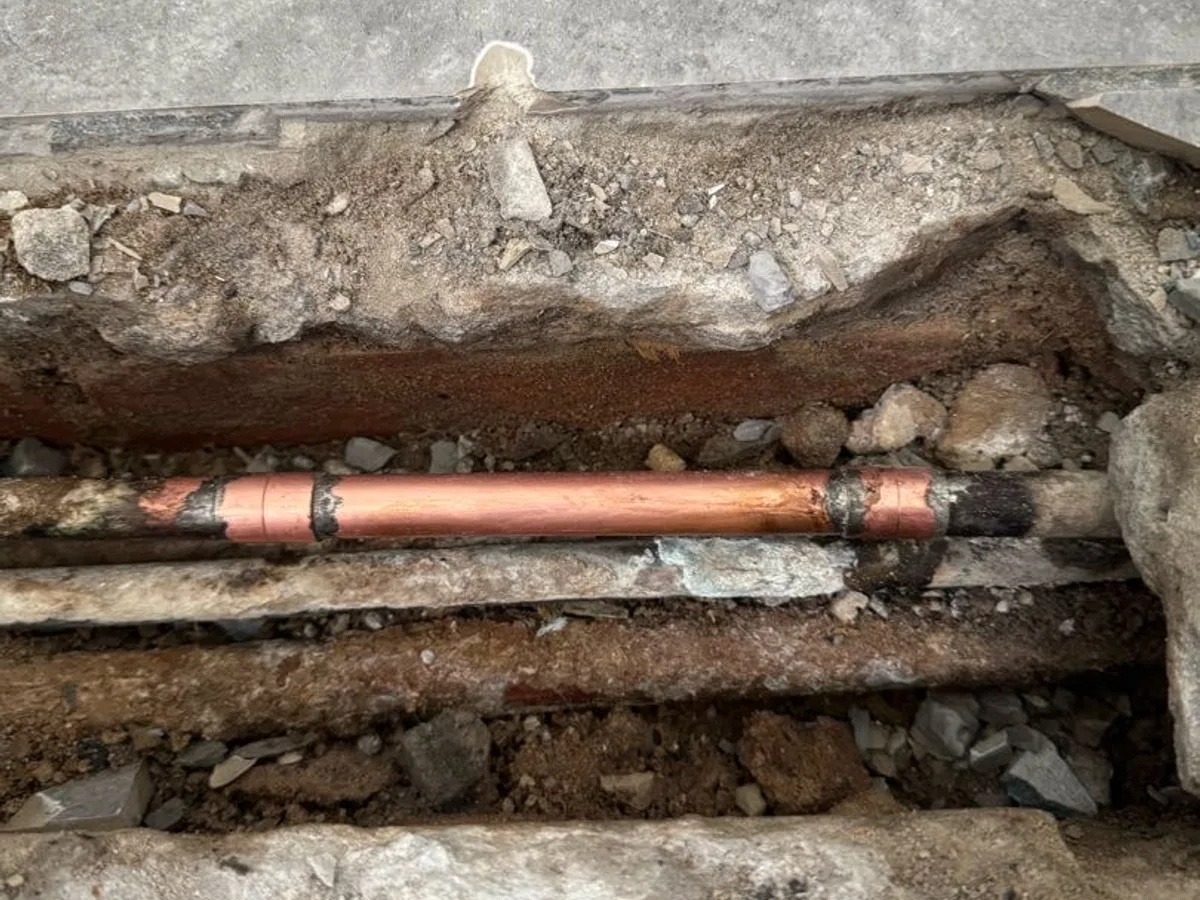 new copper pipe section with soldered fittings installed as repair completed in utility floor