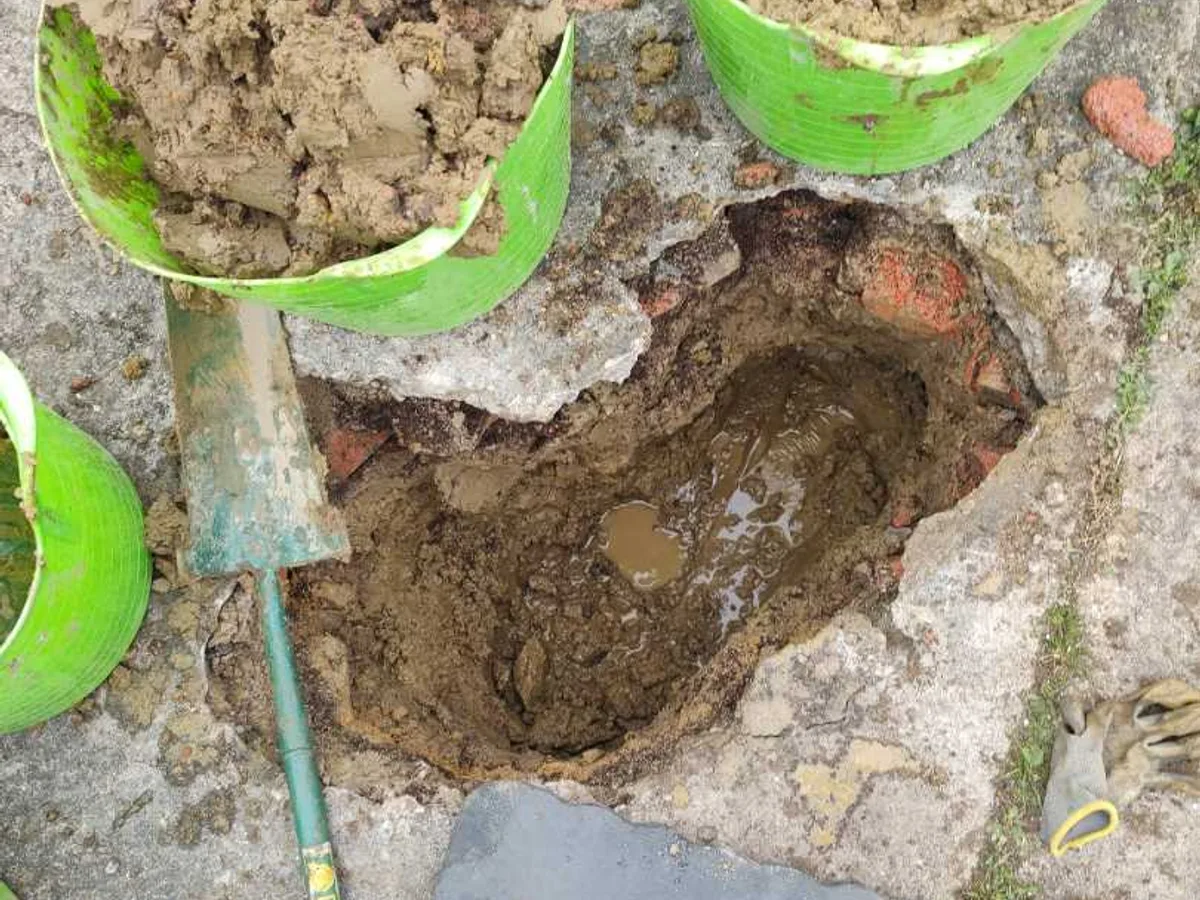 fault identified at waterlogged excavation hole through concrete driveway with spoil buckets — leak located at