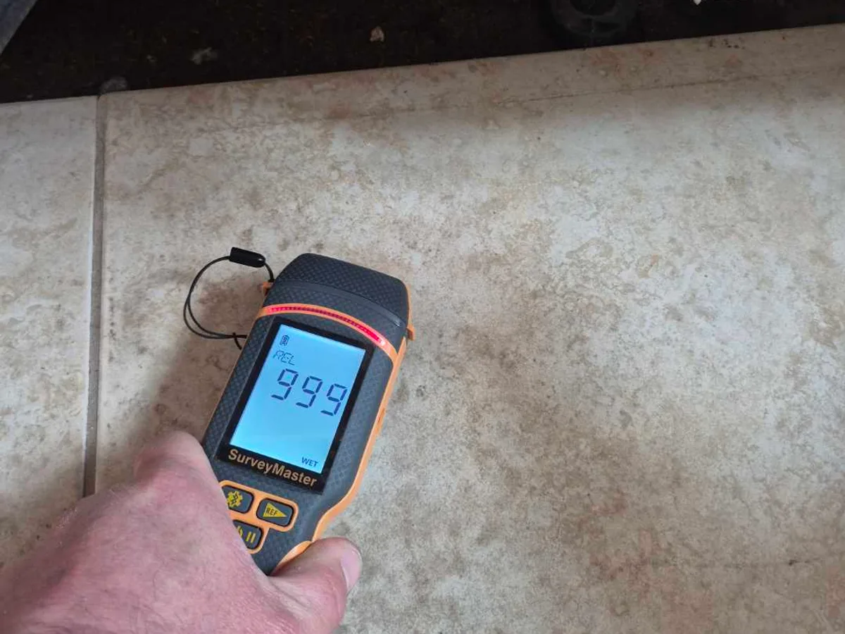 damp meter reading 999 beneath kitchen unit kickboard during leak detection survey