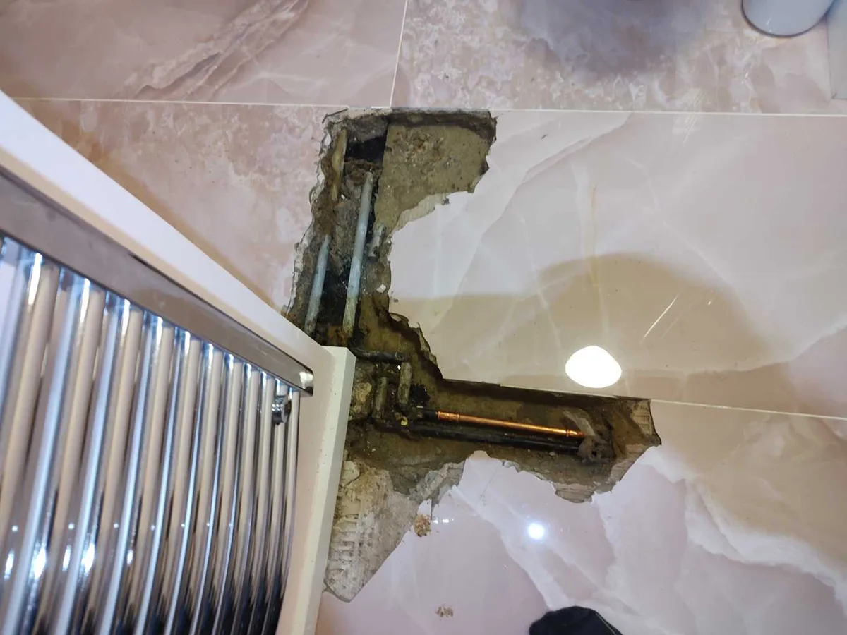 replacement copper pipe fitted in excavated bathroom floor trench as repair in progress