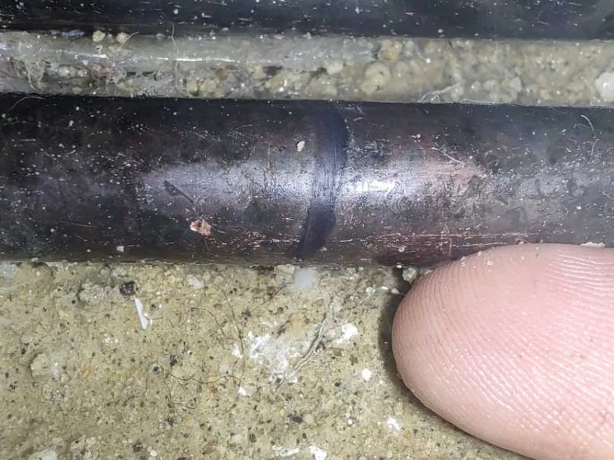 leak located at corroded 15mm copper pipe joint exposed beneath bathroom concrete floor