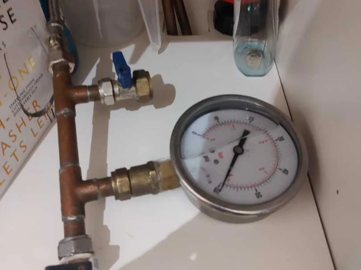 pressure gauge connected to cold feed pipework under-sink during leak detection survey